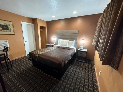 una camera d'albergo con un letto e due comodini di New Corral Motel a Victorville