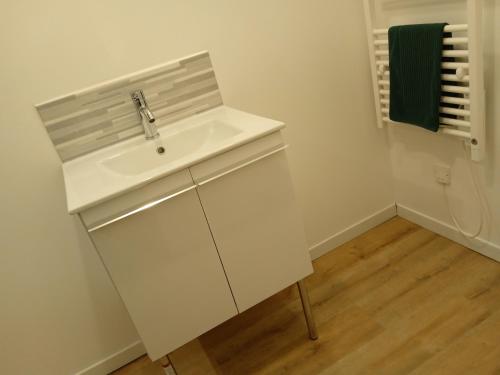 baño con lavabo blanco y toalla verde en Bienvenue à Saint Julien De Vouvantes - Dormir Comme A La Maison 
