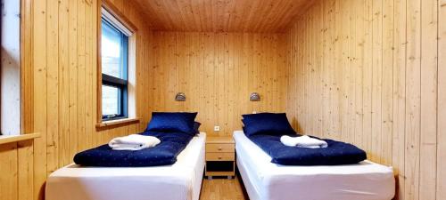 two beds in a room with blue and white pillows at Dixon Cabin nr. 7 / Dixon sumarhús nr. 7 @Kirkjubraut in Talknafjordur