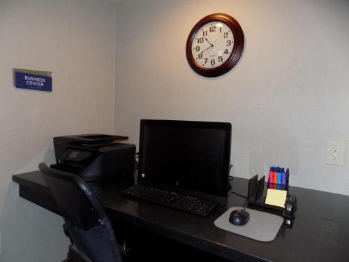 a desk with a computer and a clock on the wall at Cobblestone Hotel & Suites - Seward in Seward