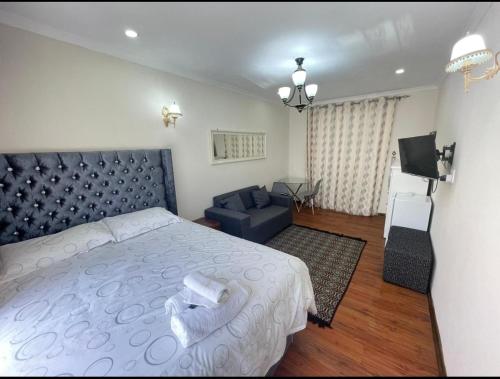 a bedroom with a large bed and a couch at Tia Maria cottage in Cape Town