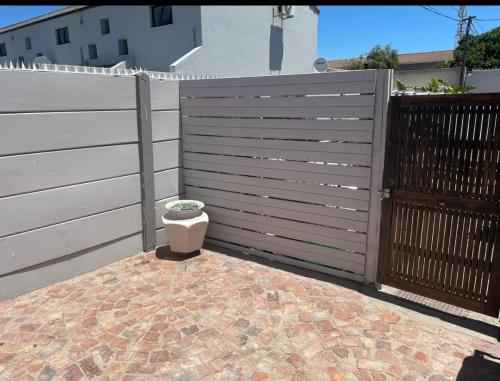 a fence with a flower pot in front of it at Tia Maria cottage in Cape Town