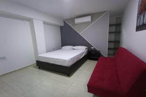a small bedroom with a bed and a red couch at Ayenda Brisas del Rio in Barranquilla