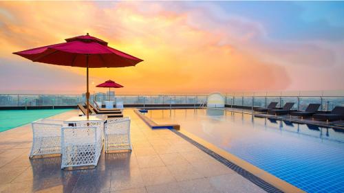 a swimming pool with an umbrella and chairs and a swimming poolvisor at Holiday Inn Dhaka City Centre by IHG in Dhaka