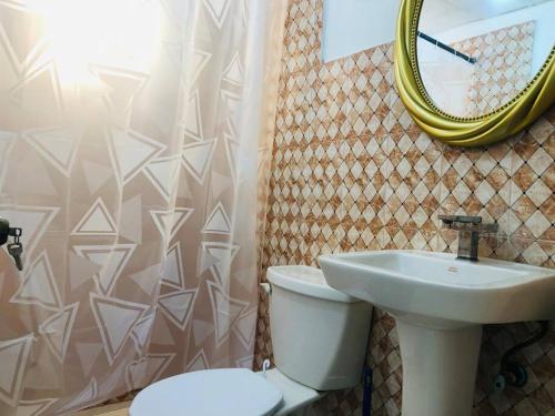 a bathroom with a sink and a toilet and a mirror at 3 bedrooms with pool & Power inverter near Malecon in La Francia