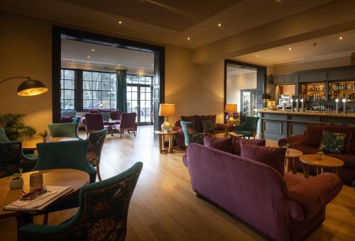 a restaurant with couches and tables and a bar at Rowton Hall Hotel and Spa in Chester