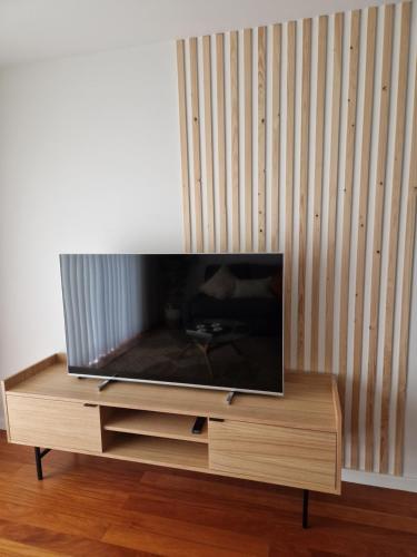 telewizor z płaskim ekranem siedzący na drewnianym stojaku w obiekcie Cristinas 2 Bedroom Apartment Caniço w Caniço