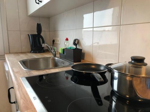 a kitchen with a stove with a pot and a sink at LIME HOMES: Balkon, Küche, Netflix in Barsinghausen