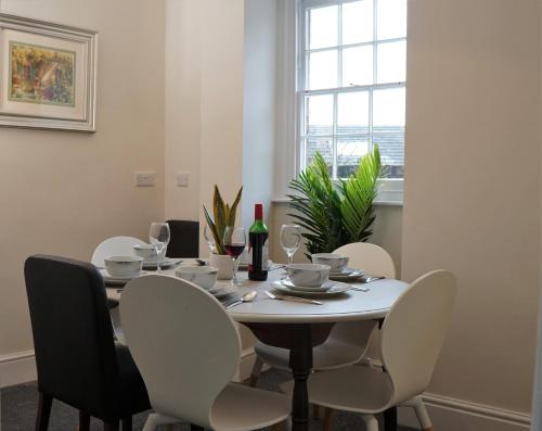 a dining room table with white chairs and a bottle of wine at Abbey Foregate in Shrewsbury