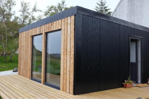 a black and wooden house on a deck at Wee Shed in Portree