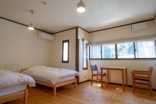 Nakasendo Ashida-Shuku Tateshina Akariya في Tateshina: غرفة نوم بسريرين وطاولة وكراسي