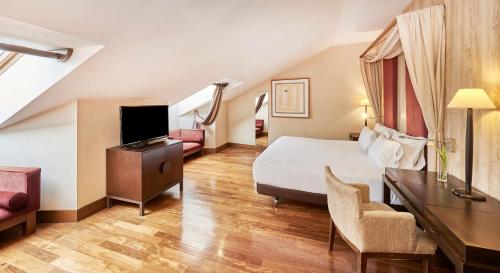 a hotel room with a bed and a desk and chair at NH Collection Palacio de Burgos in Burgos