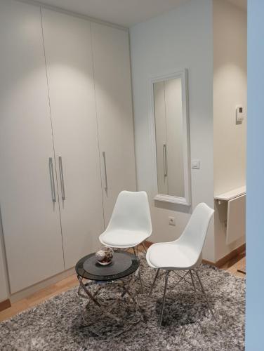 two white chairs and a table in a room at Premium Studio Apartment - Belgrade Waterfront in Sajmište