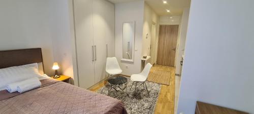 a bedroom with a bed and two white chairs at Premium Studio Apartment - Belgrade Waterfront in Sajmište
