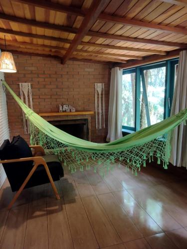 a hammock in a room with a fireplace at Pousada Pinho Bravo in Camanducaia