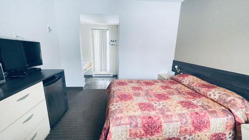 a hotel room with a bed and a flat screen tv at Motel Falcon in Brossard
