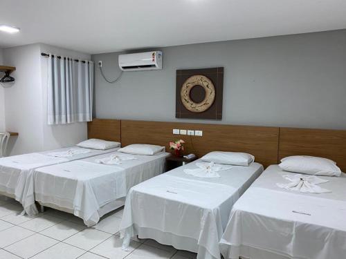 セーハ・タリャダにあるHotel Rota do Sertãoの白いリネンが敷かれたベッドが3つある部屋