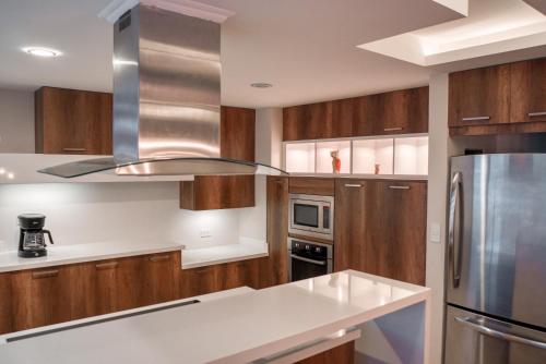 a kitchen with wooden cabinets and a stainless steel refrigerator at Penthouse Lujoso y moderno en el centro de Riobamba - Wanderlot Leganza in Riobamba