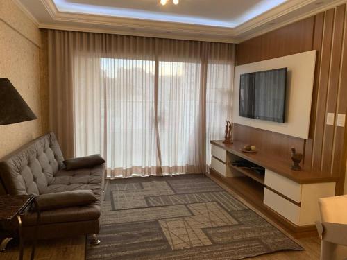 a living room with a couch and a television at Apartamento Novissimo Aquarius II in Poços de Caldas