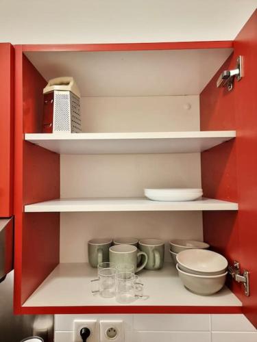 une armoire rouge avec des étagères et des bols dans l'établissement The Republik - Studio Haussmannien près du panier, à Marseille