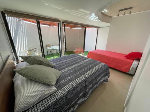 Un dormitorio con 2 camas y una ventana con una cama roja. en Departamento Península con Factura, en Iquique