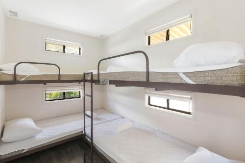 two bunk beds in a room with two windows at Reflections Moonee Beach - Holiday Park in Moonee Beach
