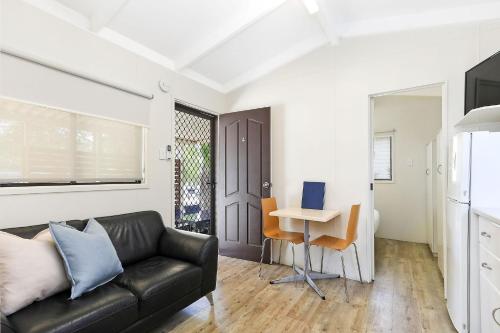 a living room with a couch and a desk with a laptop at Reflections Moonee Beach - Holiday Park in Moonee Beach