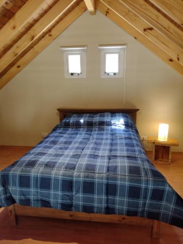 - une chambre mansardée avec un lit bleu dans l'établissement Cabaña La Encontrada, à Villa Pehuenia