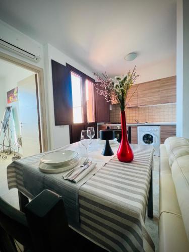 a table with a red vase with flowers on it at West Sardinia Apartments in Càbras