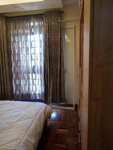 a bedroom with a bed and a window with curtains at Smarts residence in Nairobi
