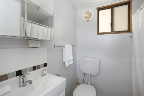 a white bathroom with a toilet and a sink at Reflections Coffs Harbour - Holiday Park in Coffs Harbour