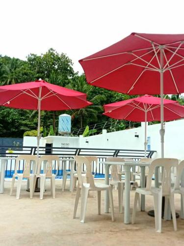 een groep tafels en stoelen met parasols op het strand bij Charming 3 bedroom Events Place with private pool in Romblon