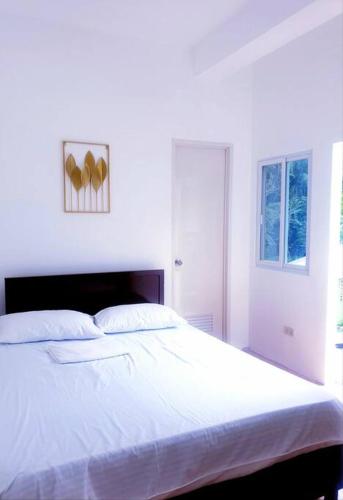 een slaapkamer met een groot bed met witte lakens bij Charming 3 bedroom Events Place with private pool in Romblon