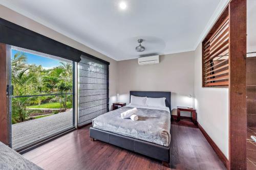 een slaapkamer met een bed en een groot raam bij Seascape Paradise in Airlie Beach