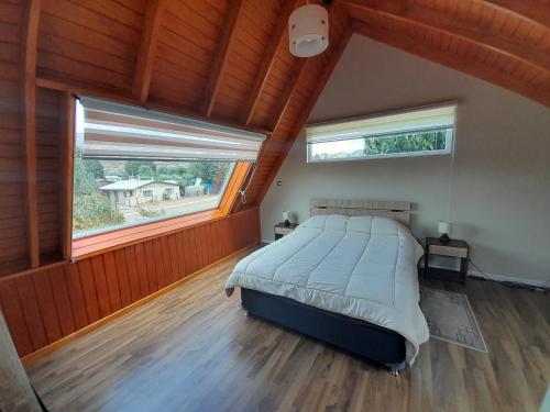 1 dormitorio con 1 cama grande y 2 ventanas en EL RINCON DE LÚ, en Chile Chico
