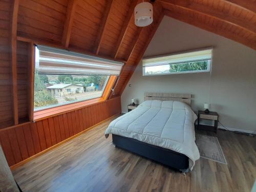 a bedroom with a large bed and two windows at EL RINCON DE LÚ in Chile Chico