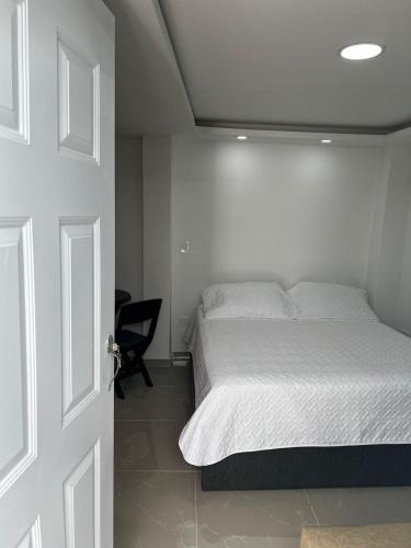 a white bedroom with a bed and a chair at SWEET BREEZE in San Andrés