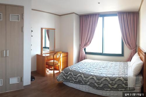 a bedroom with a bed and a desk and a window at Ilsung Condo Namhan River in Yeoju