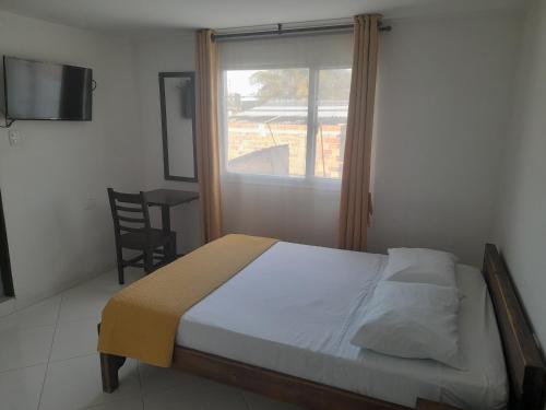 a bedroom with a bed and a window and a chair at HOTEL LA RUEDA SR in Barbosa