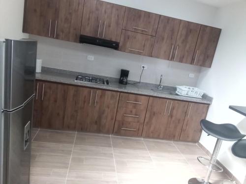 a kitchen with wooden cabinets and a stainless steel refrigerator at Apartamentos LM in Santa Rosa de Cabal