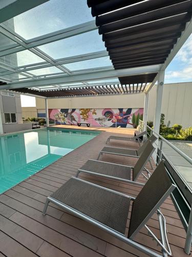 a deck with lounge chairs next to a swimming pool at Entire Luxurious Apartment in Shopping Mall in Mexico City