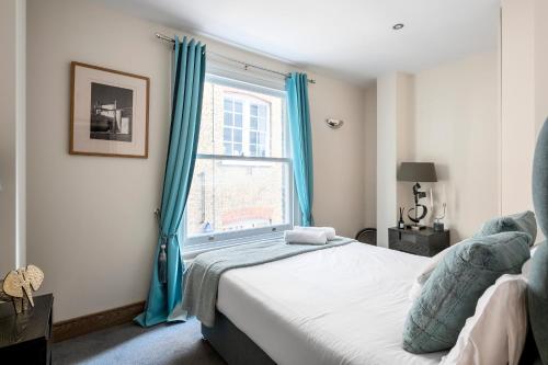 a bedroom with a bed and a window with blue curtains at Covent Garden gem apartment in London