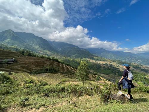 a woman sitting on a rock looking at a valley at SaPa Big Tree Hmong Homestay in Sa Pa