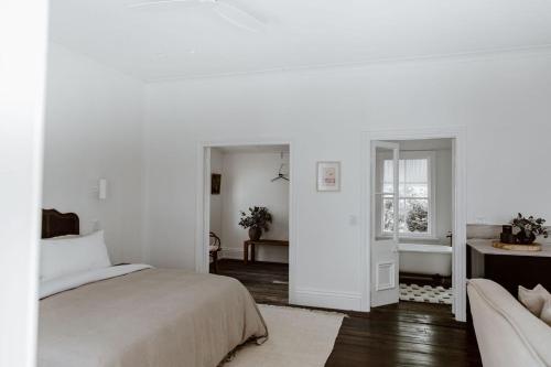 a white bedroom with a bed and a window at The Postman's Cottage - Hinterland Luxury in Montville