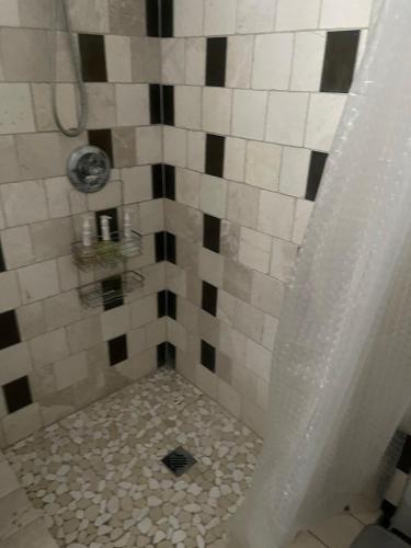a shower with a tiled floor and a shower curtain at Serenity home in Laplace