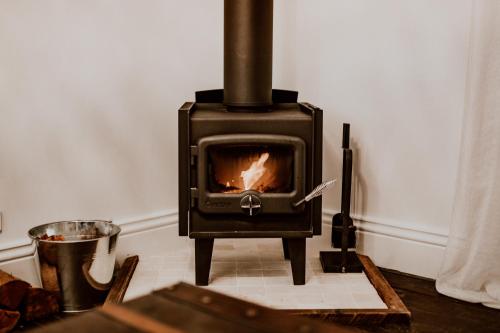 a wood stove in a room with a table at The Postman's Cottage - Hinterland Luxury in Montville