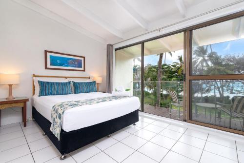 a bedroom with a bed and a large window at Seascape Holidays at Beachfront Terraces in Port Douglas