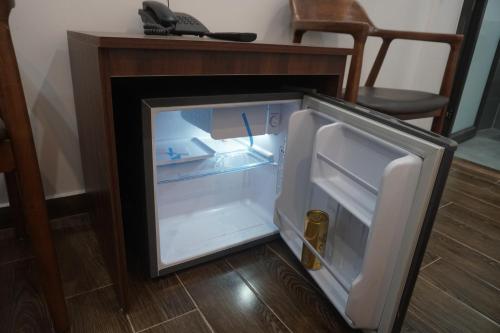 an empty refrigerator with its door open next to a desk at Adal Motel in Kiến An