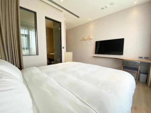 een slaapkamer met een groot wit bed en een flatscreen-tv bij alfar Hotel in Dayuan