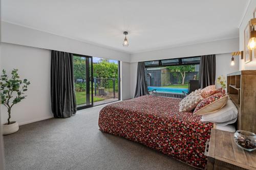 a bedroom with a bed and a large window at Little Big House - Rotorua Holiday Home in Rotorua